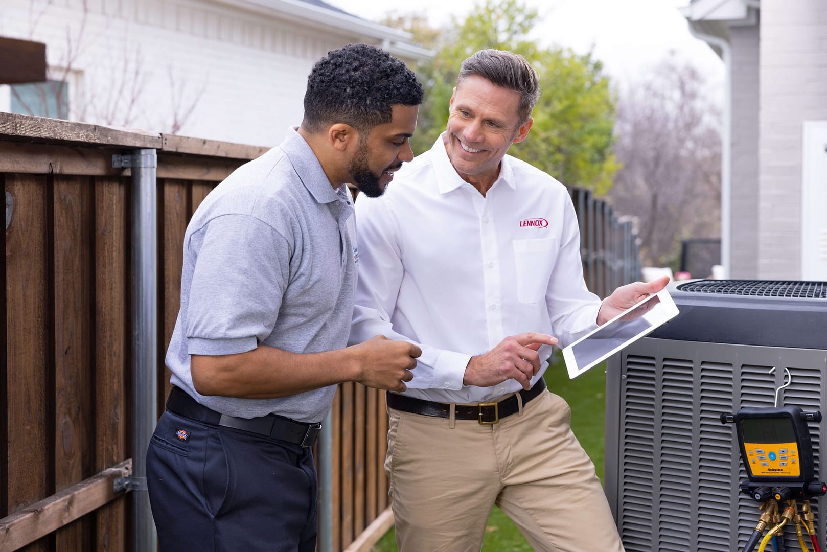 HVAC technician explaining outdoor AC system service to a homeowner during an air conditioning inspection.