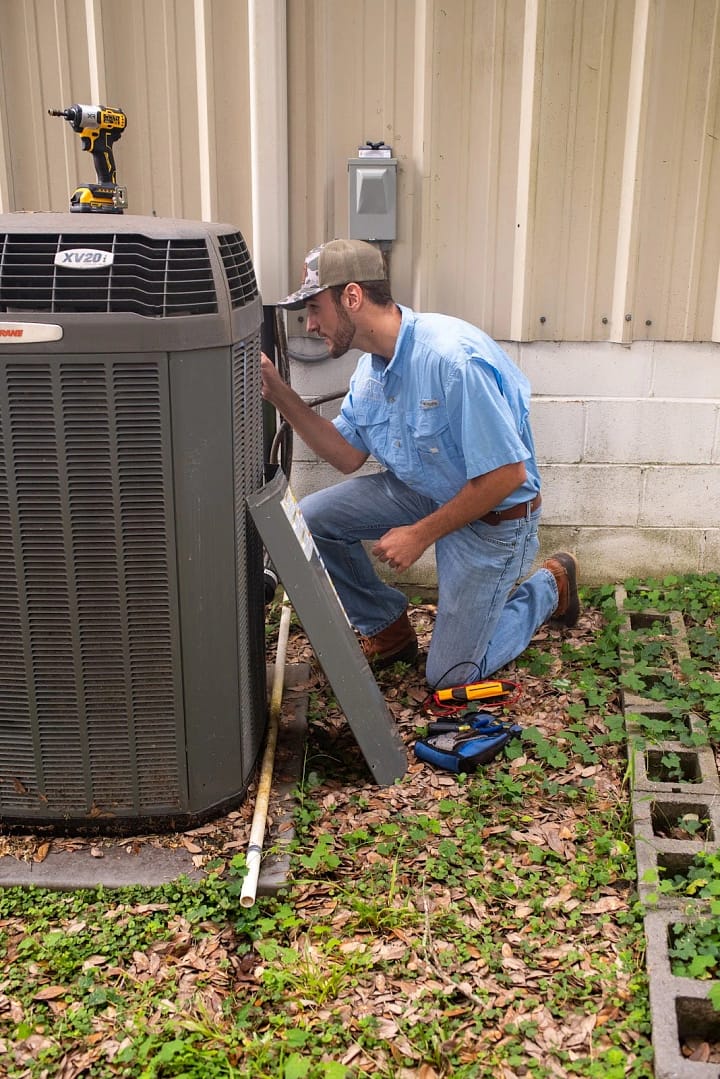 A Deal HVAC technician repairing an outdoor HVAC system